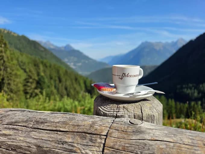 Coffee cup on wooden post with alpine mountain landscape in background