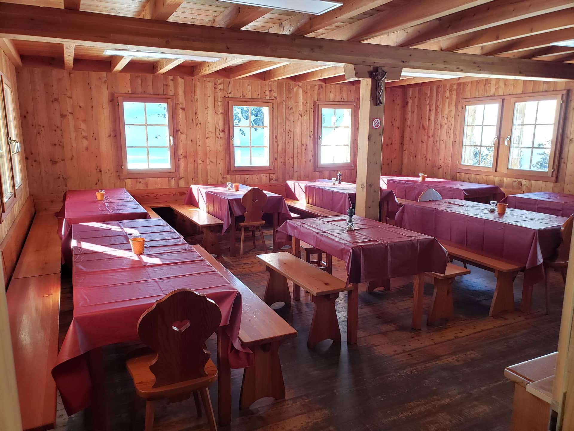 Wooden dining interior with tables covered in red cloths at Cabane de Prafleuri