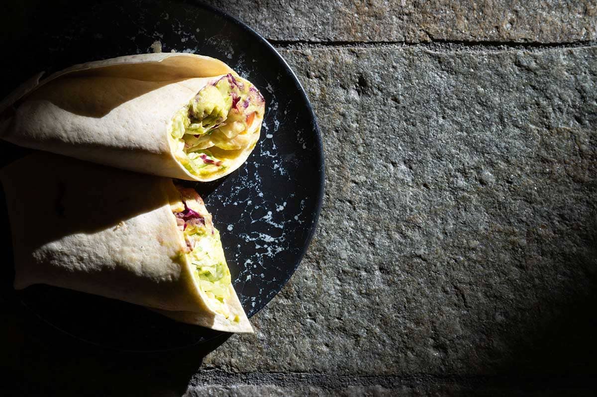 Take-away wrap filled with vegetables on a dark plate