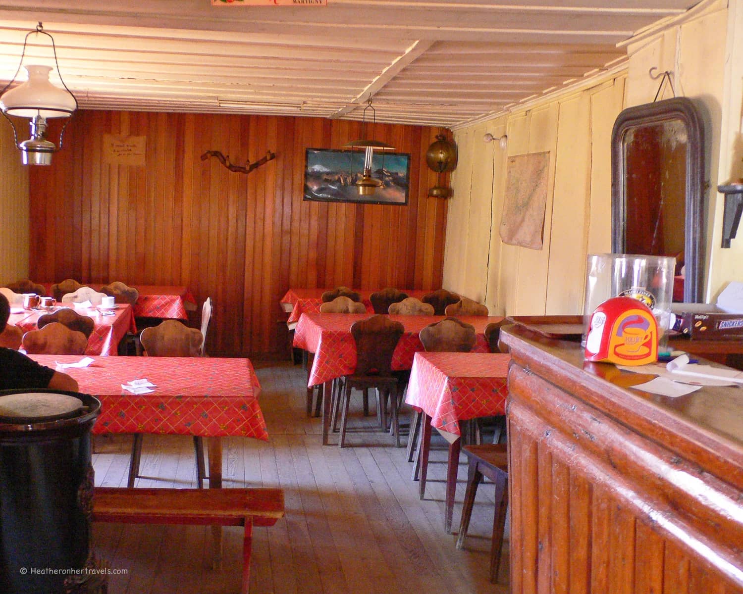 Refuge du Col de Balme alpine hut interior with wooden walls and red checkered tablecloths