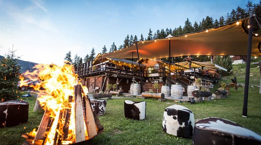 Restaurant Chez Dany with outdoor seating, bonfire pit, and string lights in mountain setting