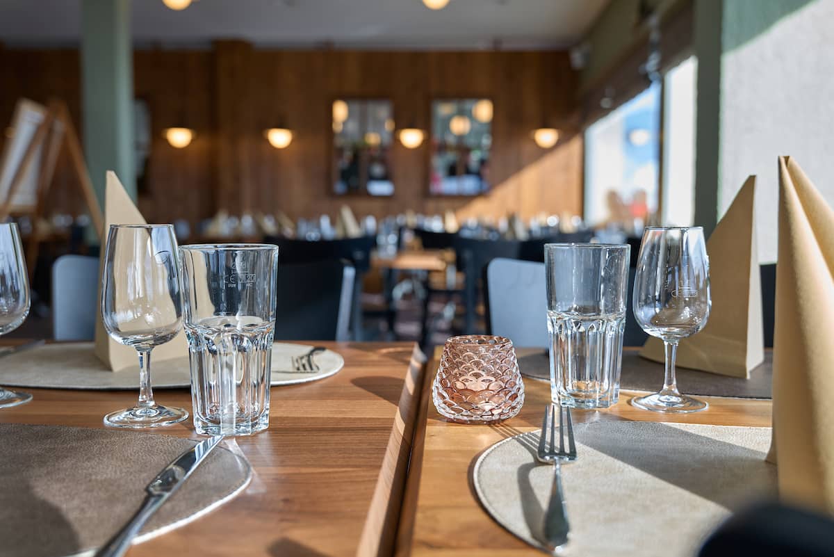 Restaurant de Sorebois interior with set wooden dining tables, glasses, cutlery, and napkins