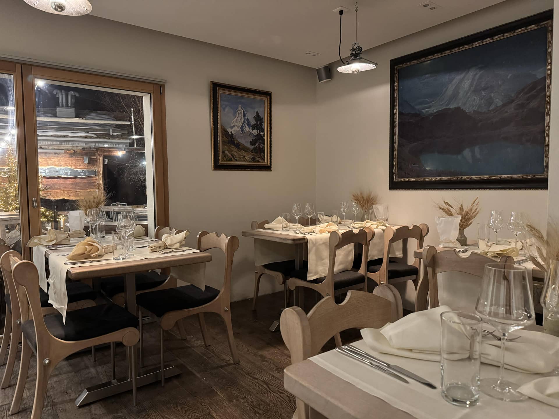 Restaurant interior with wooden tables and framed mountain landscape paintings