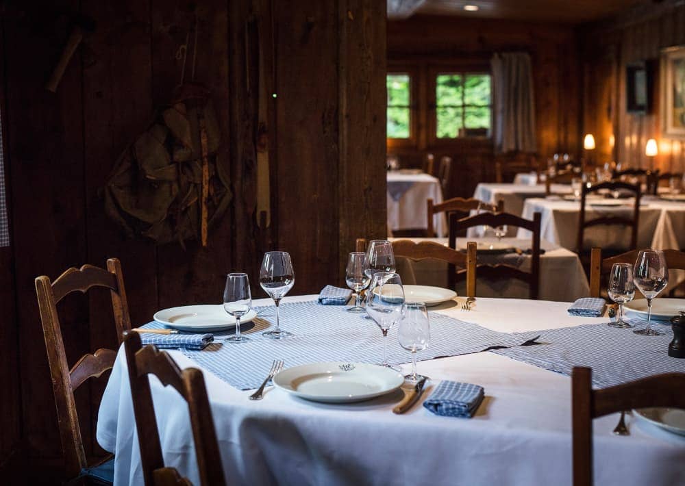 Restaurant interior with set dining tables and rustic wooden walls at Maison Carrier