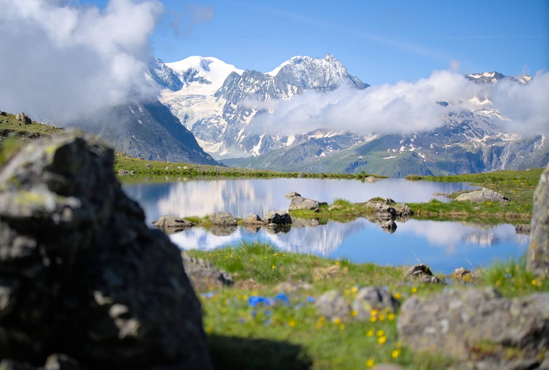 Alpine mountain lake reflecting snow-capped peaks and clouds