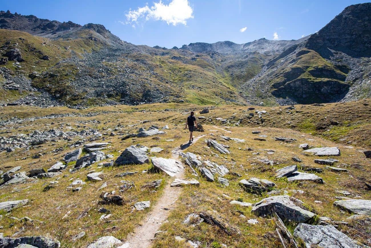 Hiker walking on rocky trail through mountain pass