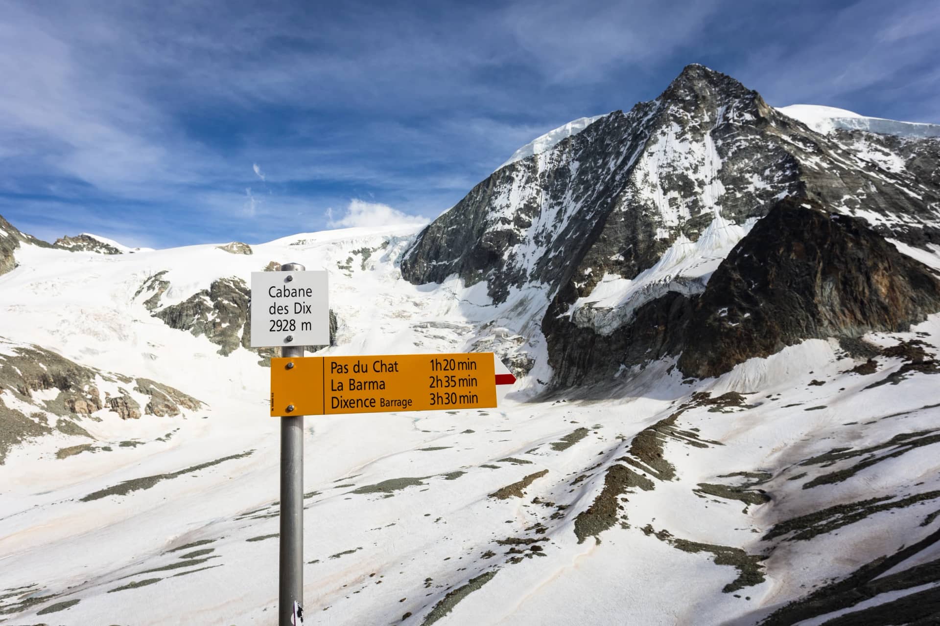 Hiking trail distance sign with the Mont Blanc de Cheilon peak, at 3870m, in Canton Valais in the Swiss alps in Switzerland on a sunny summer day