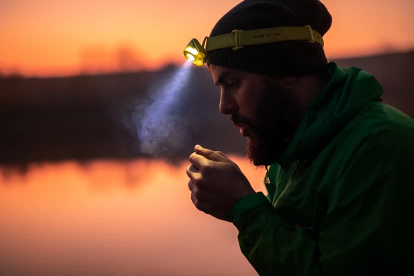 Hiker with headlamp warming up hands in evening