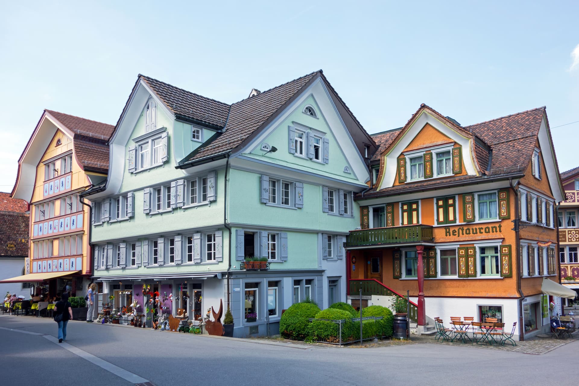 Colorful historic buildings lining a street in Appenzell with outdoor cafe seating and shops.