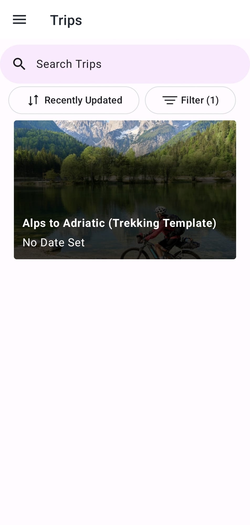 Cyclist riding mountain bike past alpine lake and mountains
