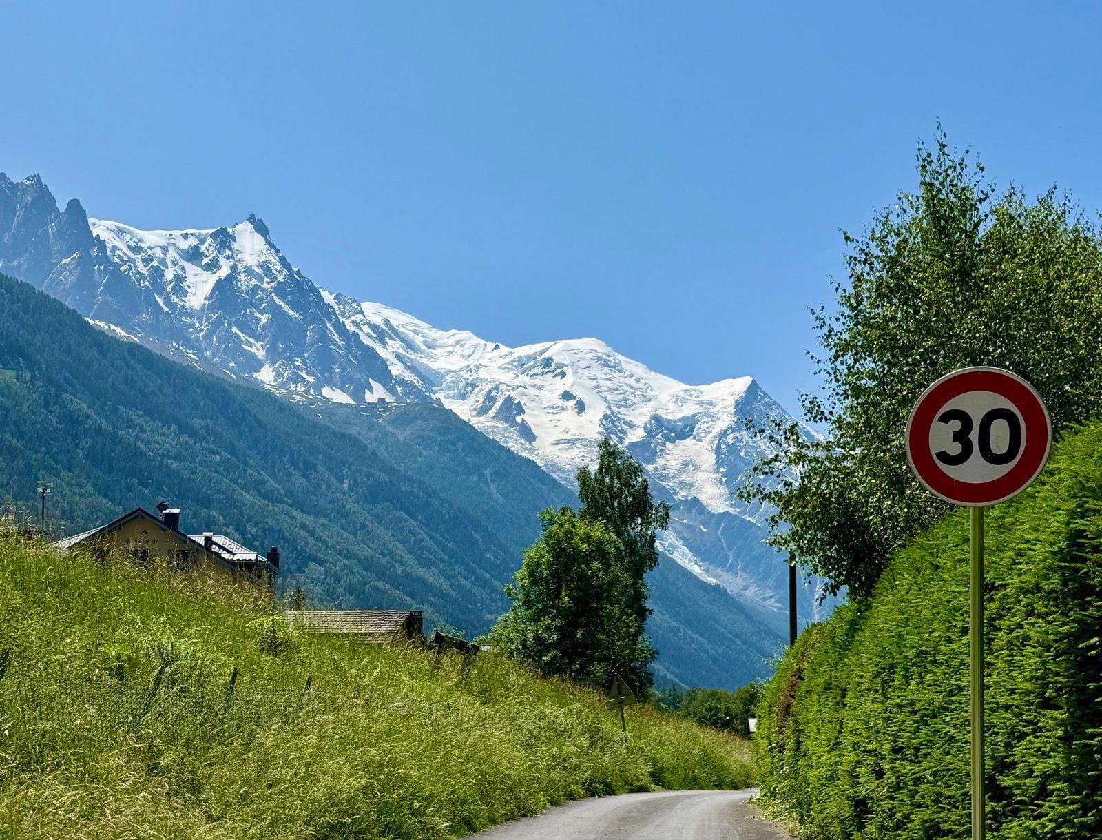 Speed limit 30 sign on rural road with snowy mountain peaks in background