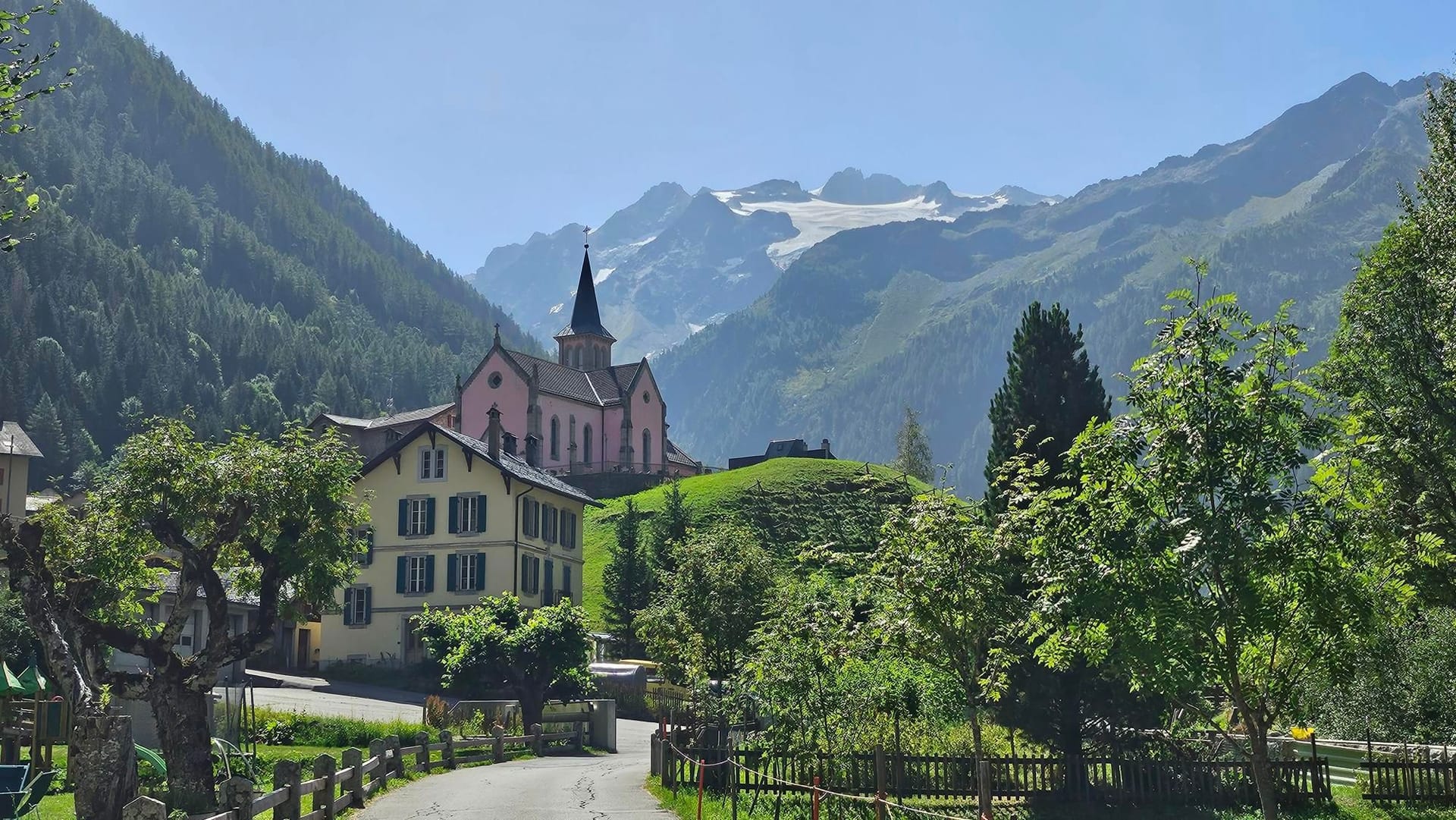 Fen Tred D'Arpette alpine village with pink church and snowy mountain peaks