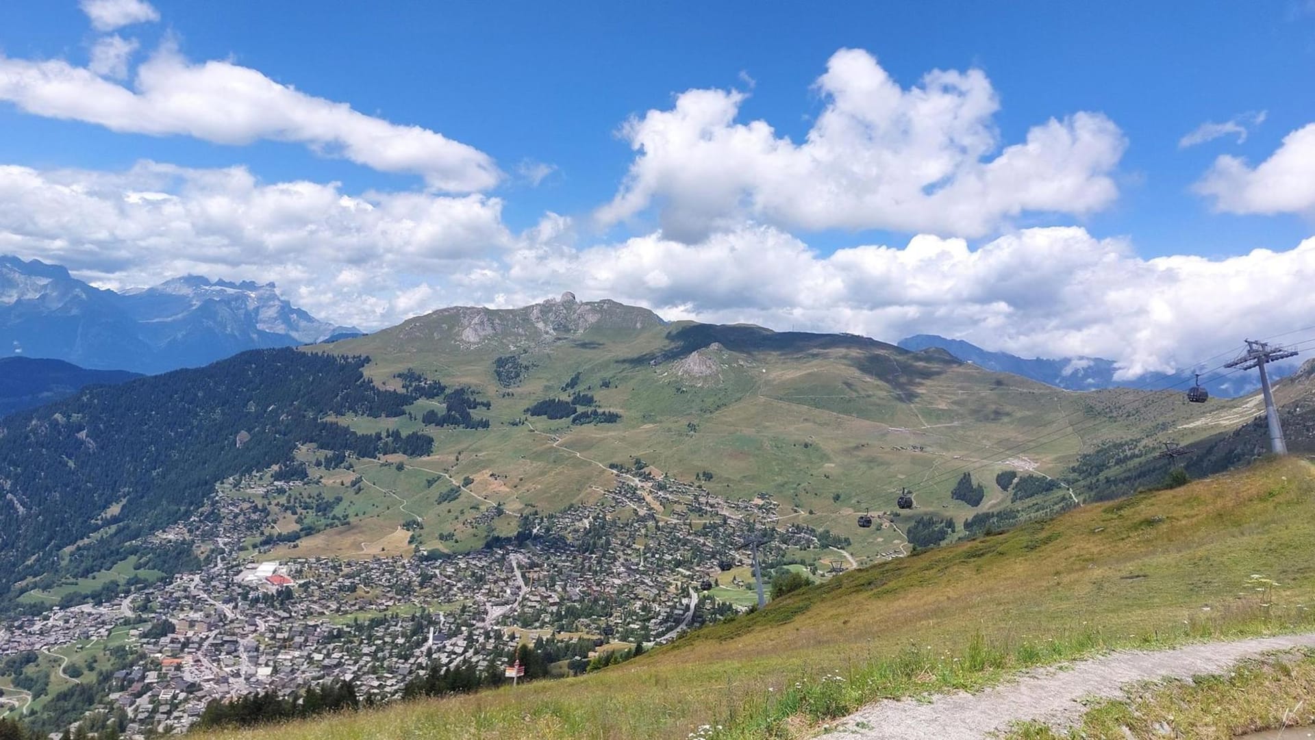Alpine village in a mountain valley with ski lifts and blue sky with clouds