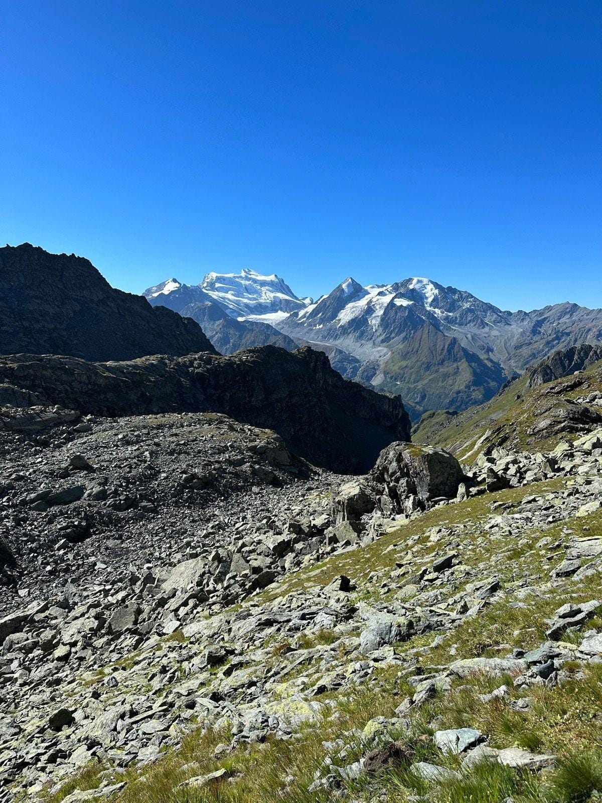 Alpine mountain peaks with snow and rocky terrain under clear blue sky
