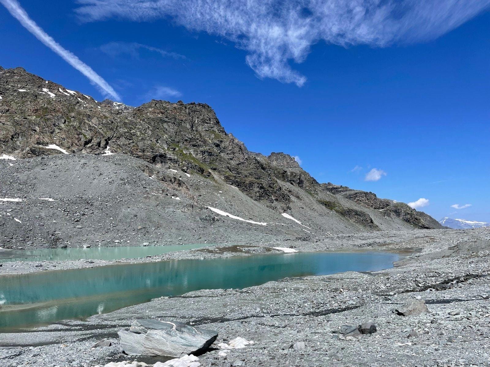 Alpine mountain peaks with rocky terrain and turquoise glacial lake under blue sky