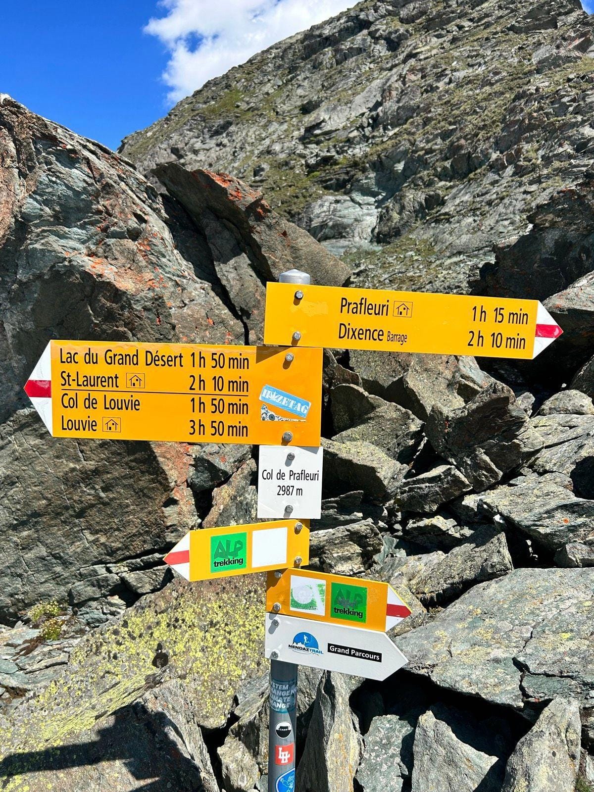 Yellow hiking trail signposts pointing to destinations in alpine mountain terrain