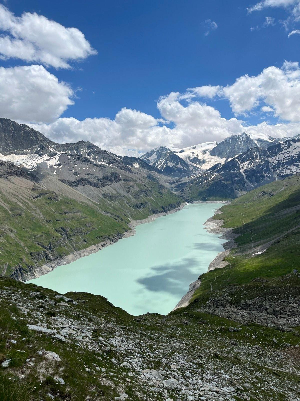 Turquoise alpine lake nestled in a valley between snow-capped mountain peaks