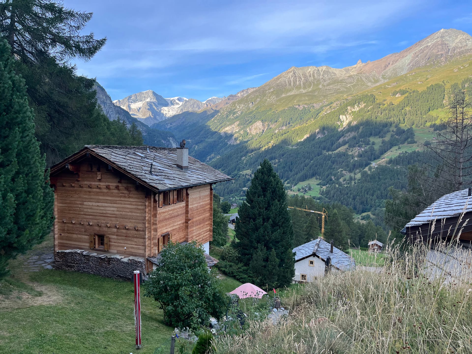 Wooden alpine chalet in mountain valley with snow-capped peaks