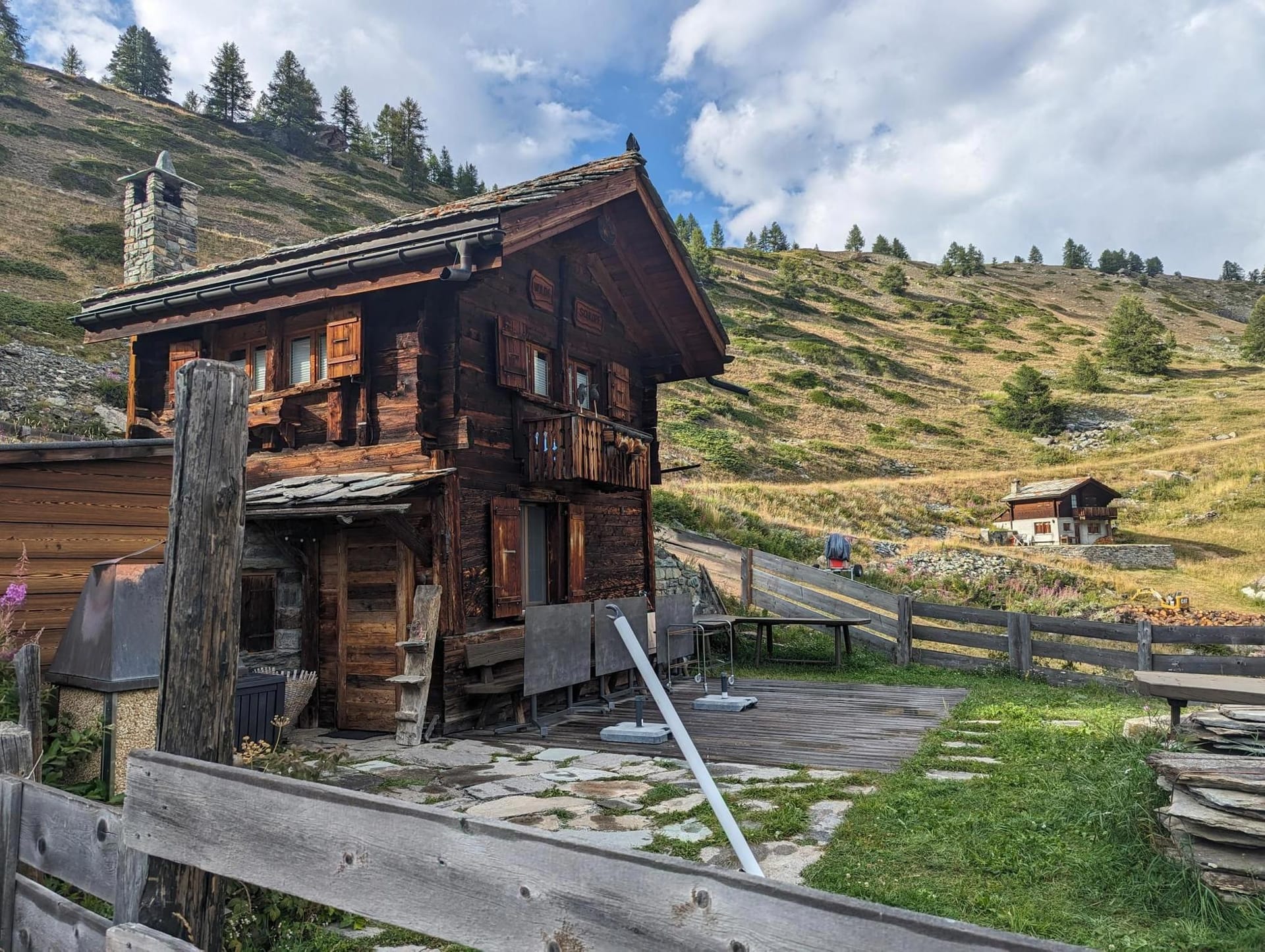 Wooden alpine chalet in mountain landscape with stone roof and stone chimney