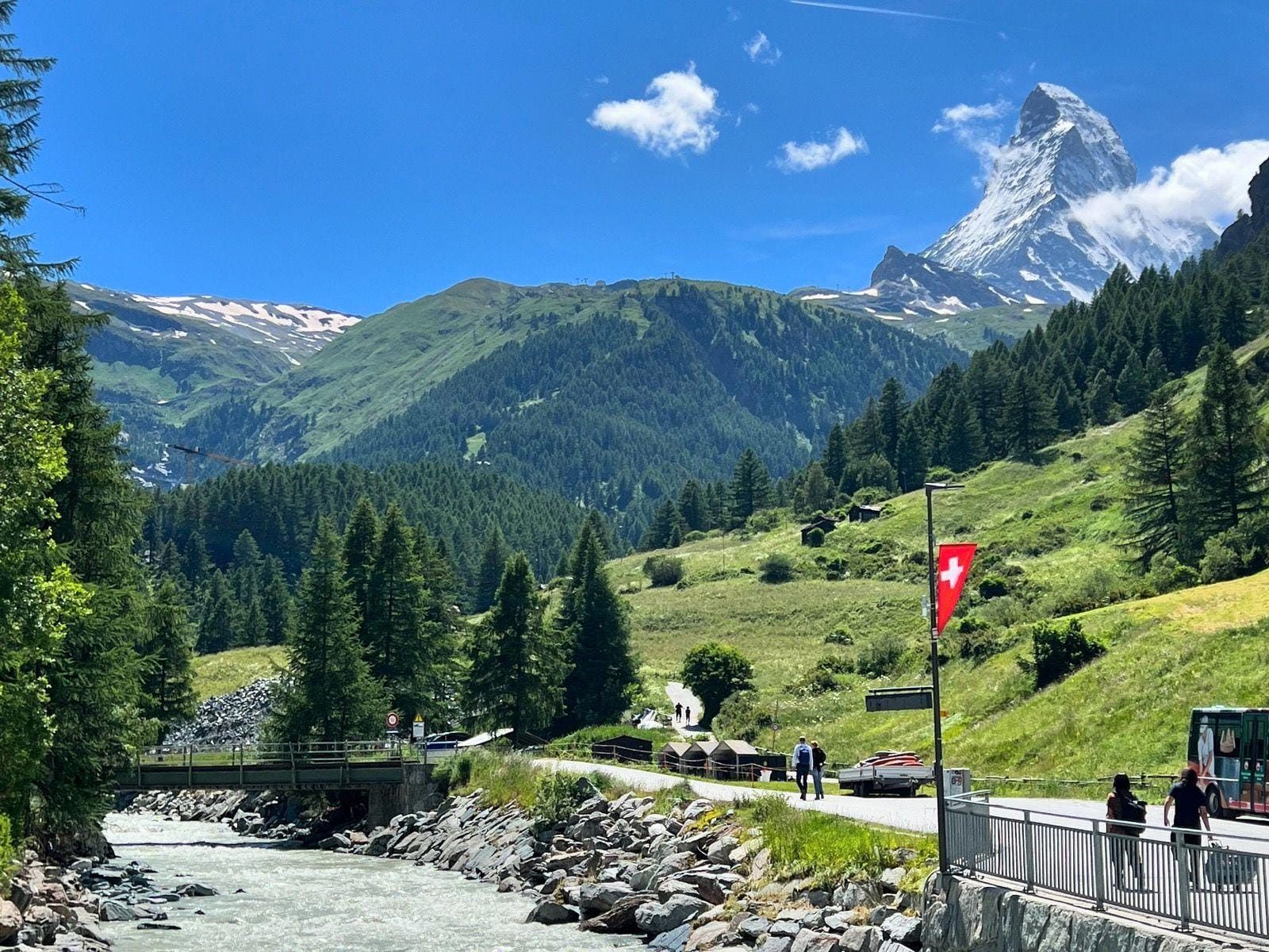 Matterhorn mountain peak with snow, green alpine hills, and a river in Switzerland