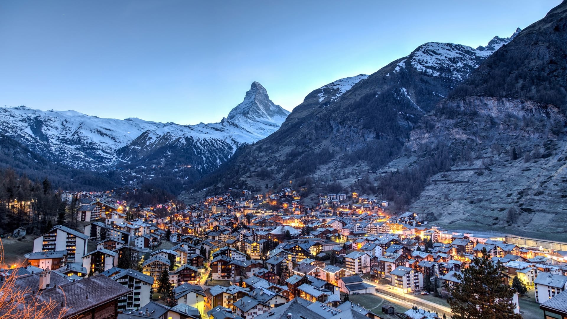 Zermatt alpine village illuminated at dusk with the Matterhorn peak and snow-covered mountains