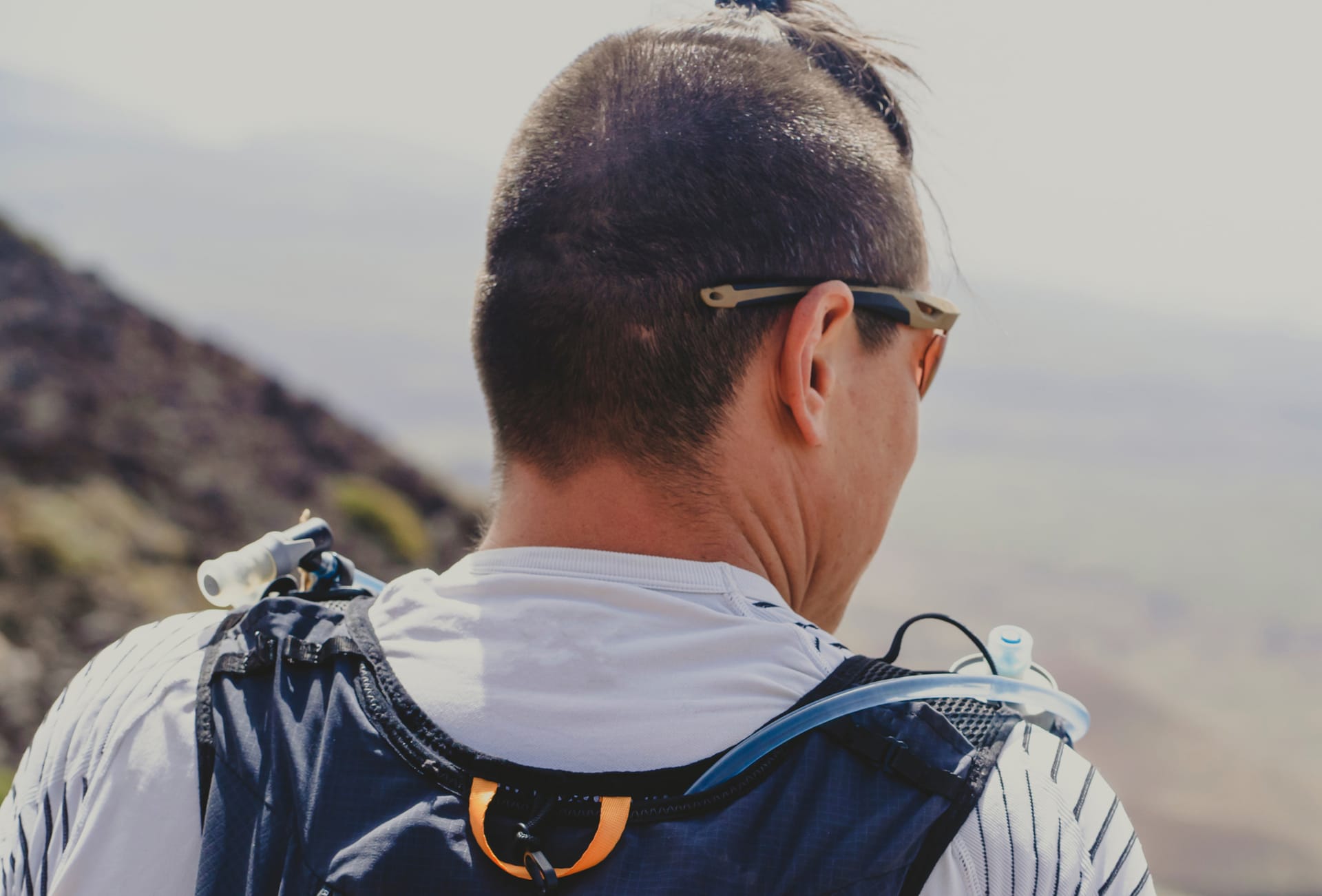 Hiker wearing a hydration pack and sunglasses in mountain setting
