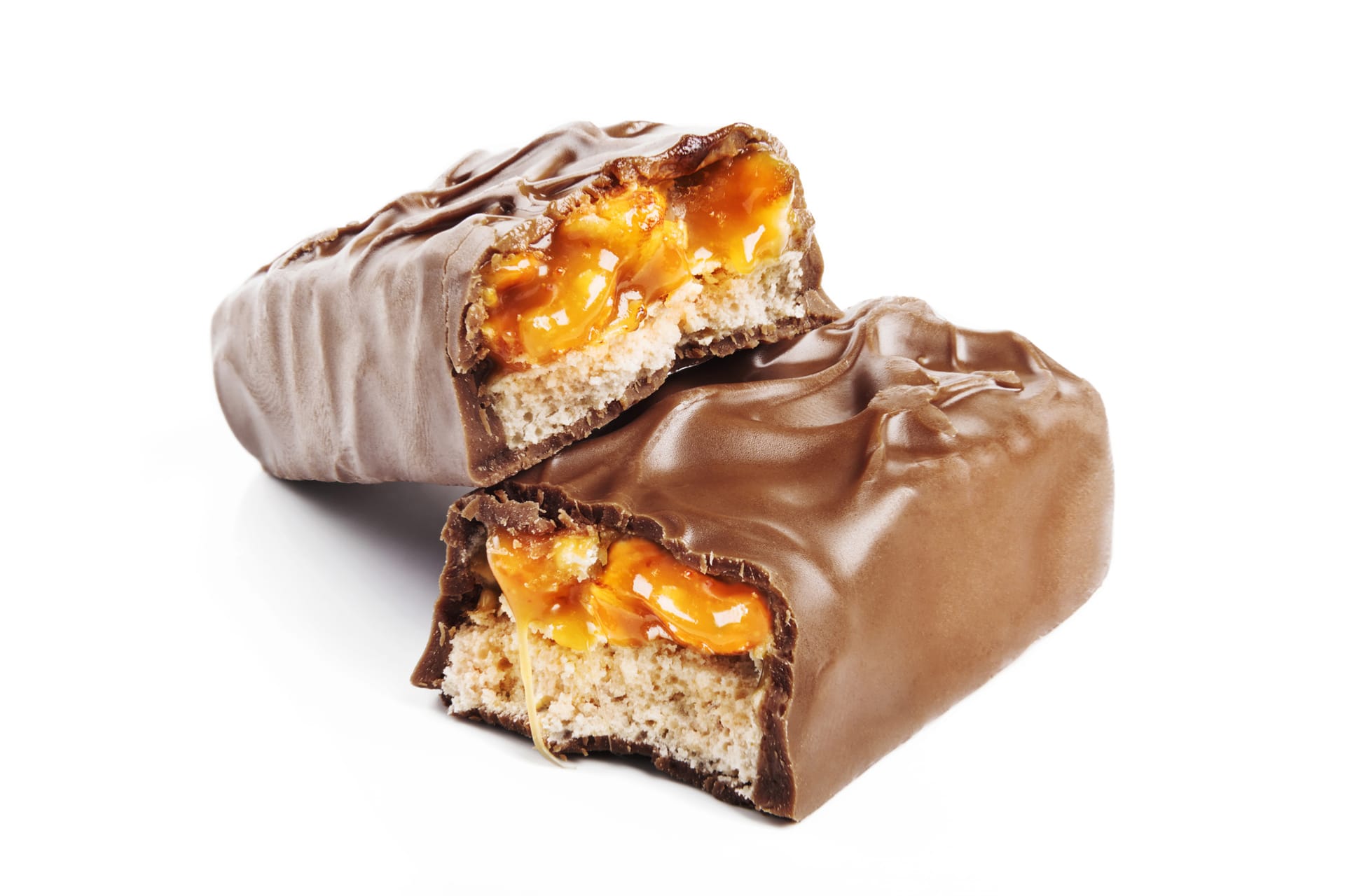 Chocolate bar cut in half revealing caramel and nougat layers on white background