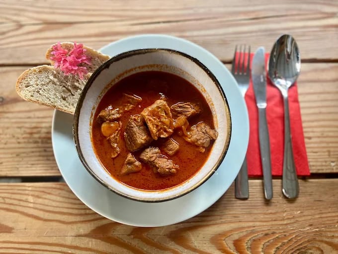 Bowl of beef stew with bread on wooden table