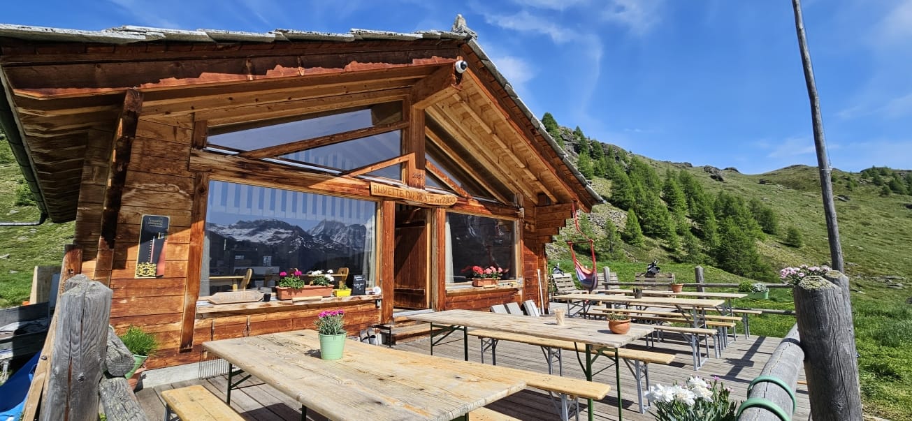 Wooden alpine chalet with outdoor picnic tables on a sunny day in the mountains