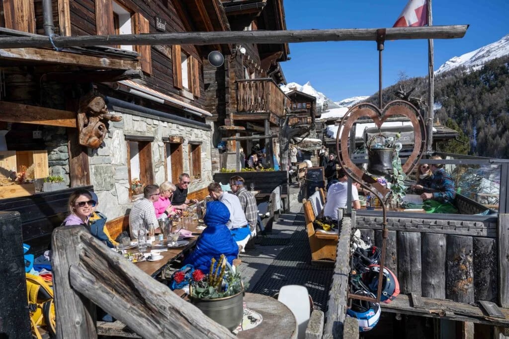 Outdoor dining at Findlerhof alpine restaurant with snowy mountain background