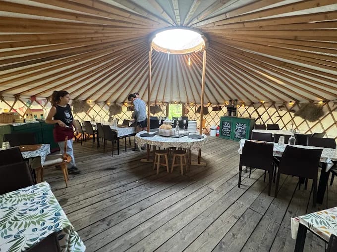 Interior of yurt dining room at Refuge Le Peuty with wooden floor and tables