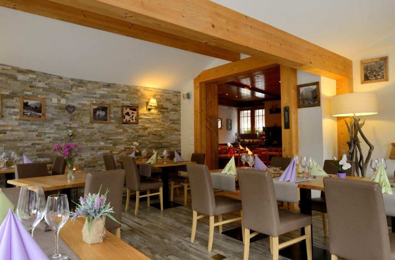 Restaurant interior with wooden beams, stone wall, and set dining tables