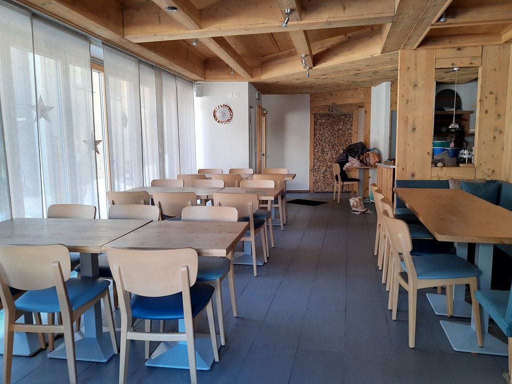 Restaurant interior with wooden tables, chairs with blue cushions, and exposed wood ceiling beams