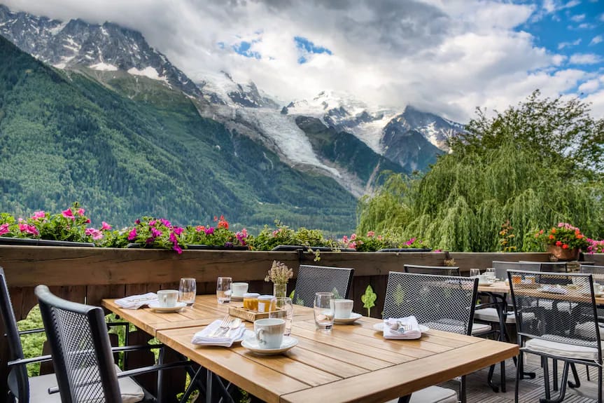 Outdoor dining terrace with breakfast setup and snow-capped mountain views