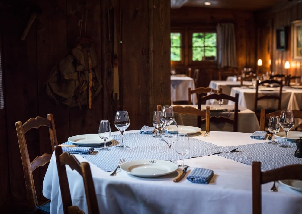 Restaurant interior with set dining tables and rustic wooden walls at Maison Carrier