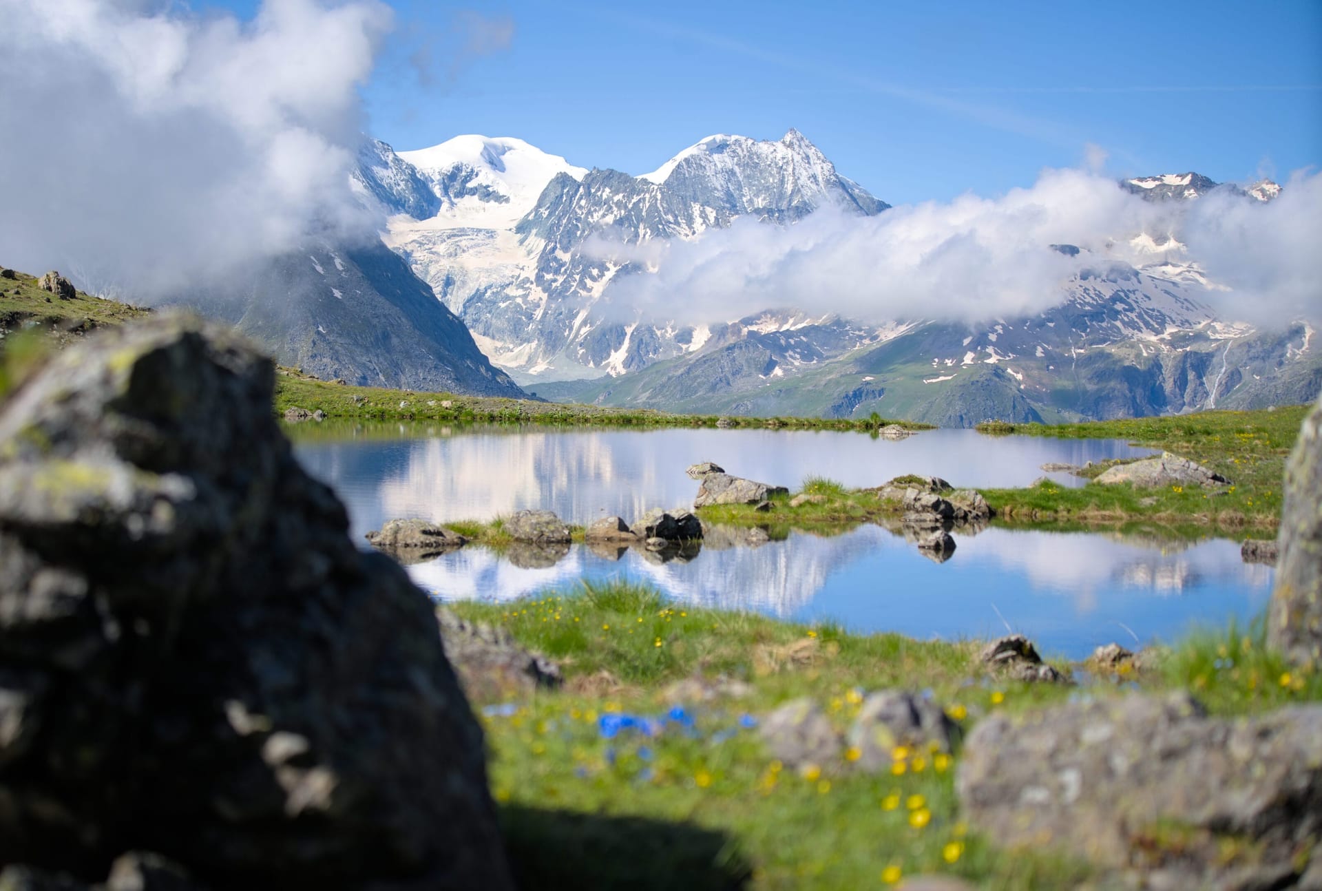 Alpine mountain lake reflecting snow-capped peaks and clouds