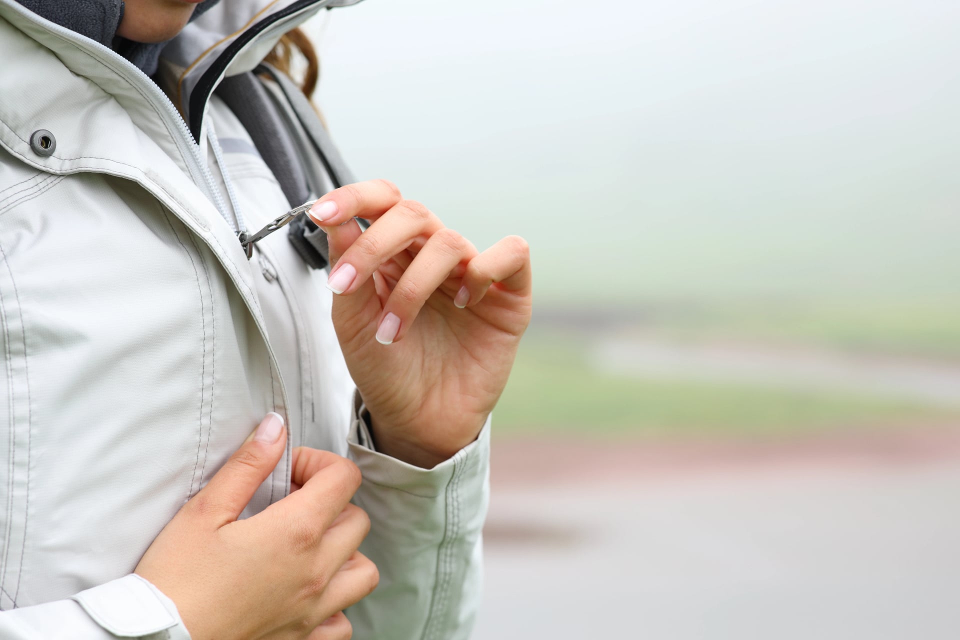 Trekker zipping up jacket in the mountain a foggy day