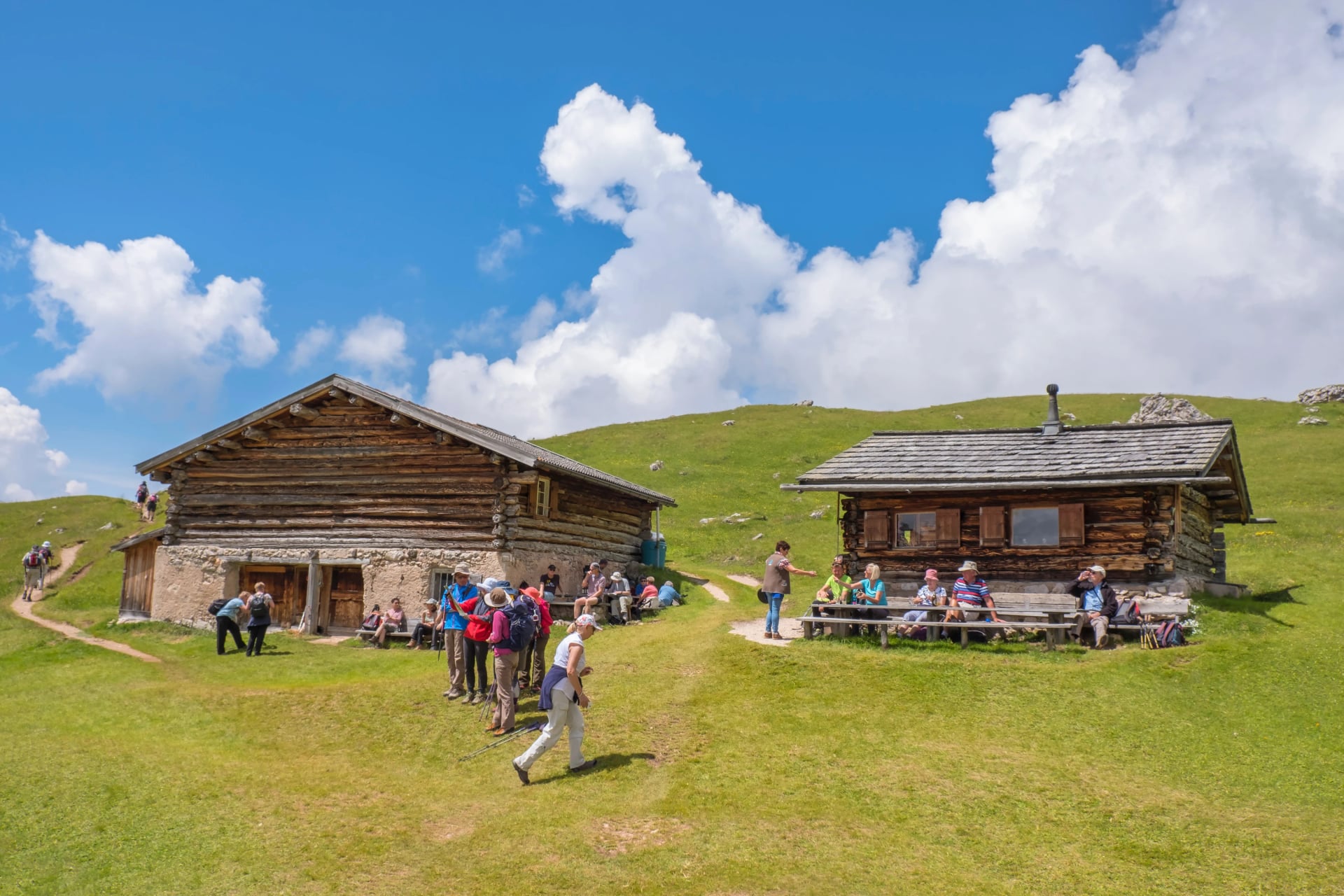 Fjällstuga med vandrare på en alpmatta