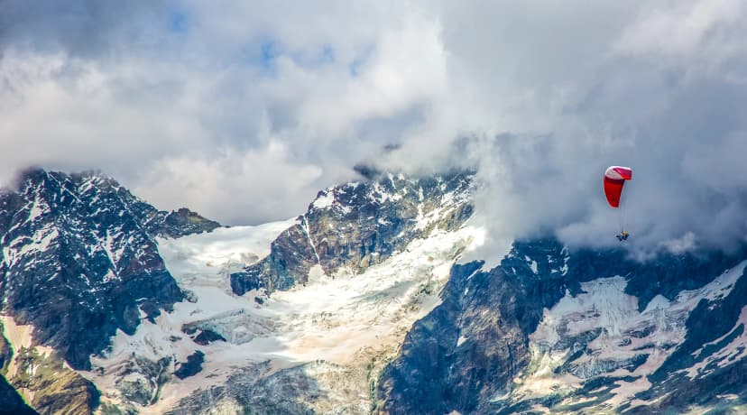 A para glider sails over the Ober Gabelhorn (4063 m). It is a mountain in the Pennine Alps in Switzerland, located between Zermatt and Zinal.