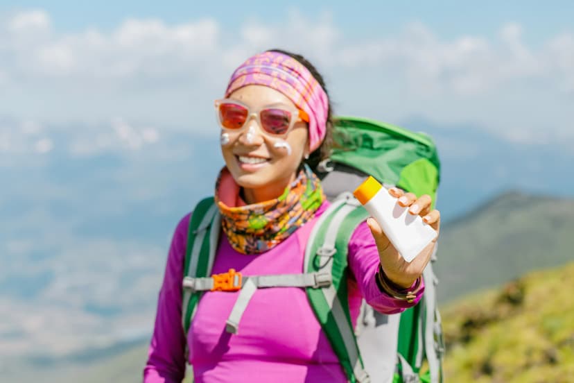Hiker woman applying sun cream to protect her skin from dangerous uv sun rays high in mountains. Travel healthcare concept