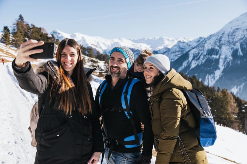 Happy family in winter taking a picture outdoors with the mountains in the background.