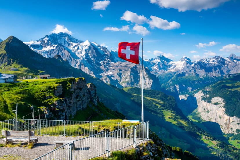 Swiss flag waving on the top of Mannlichen mountain with views of the Jungfrau region in the background