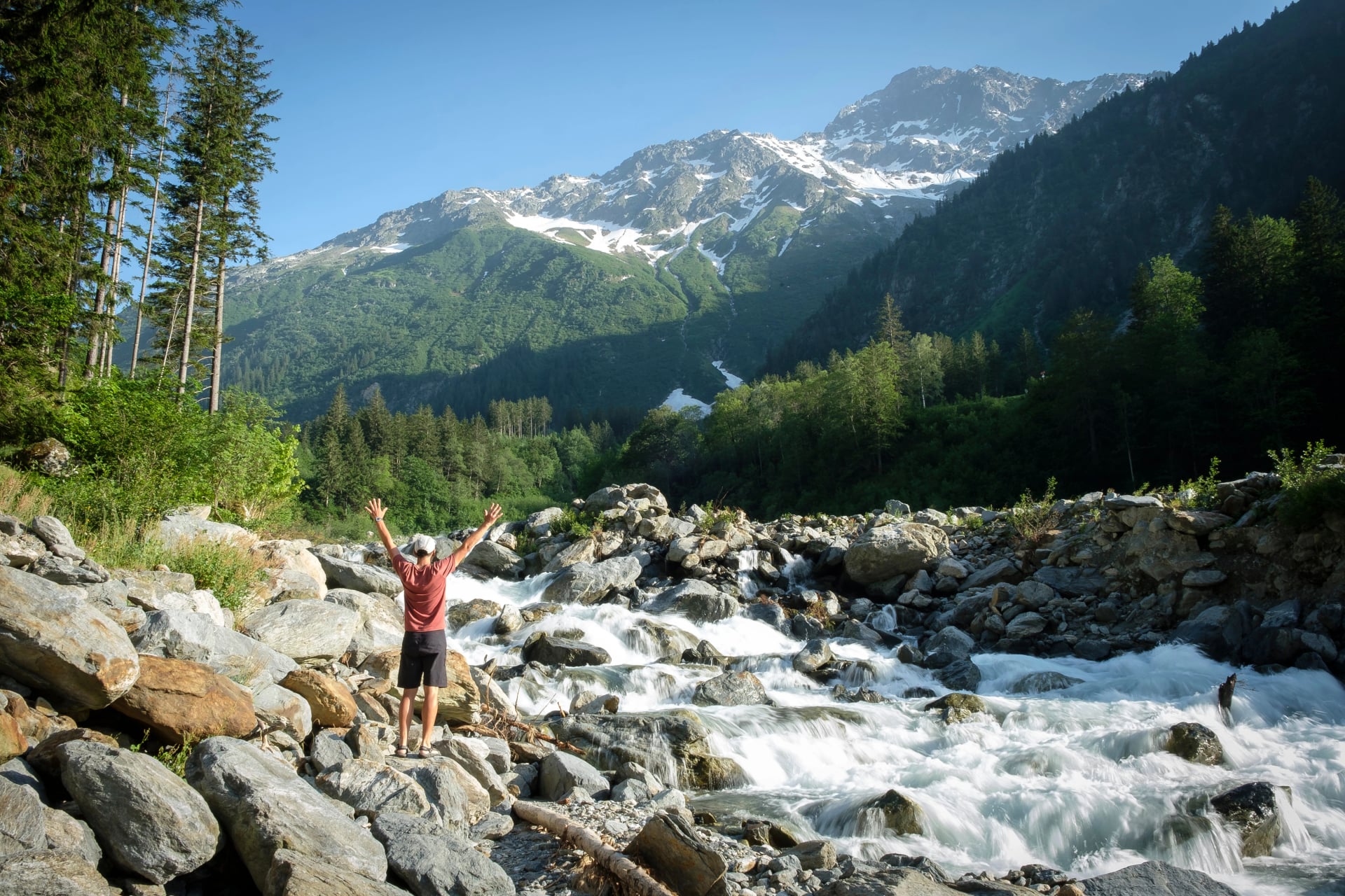 A hiker stands on the wild Aare in the Bernese Oberland and looks out over the Swiss Alps