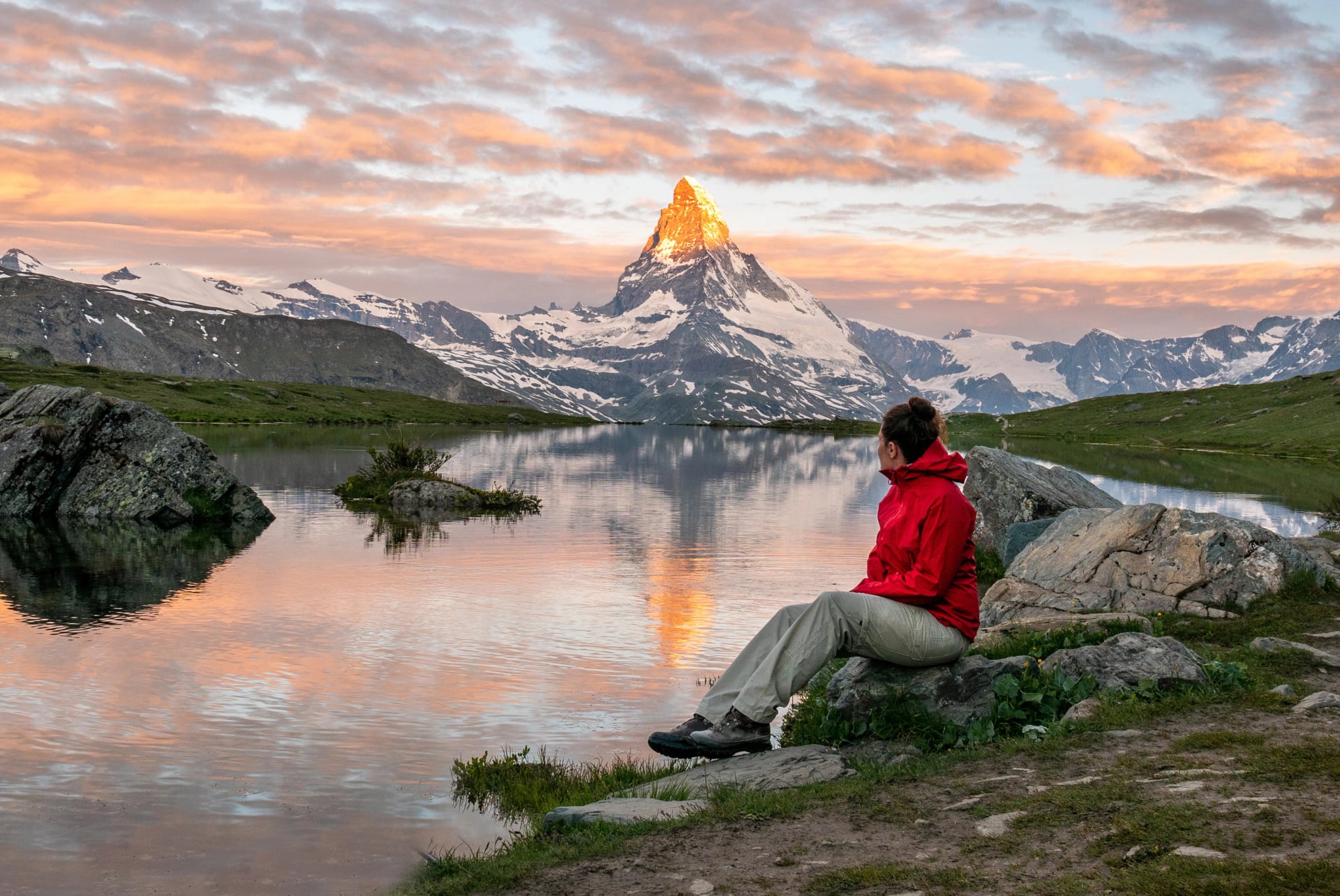 Morning shot of the golden Matterhorn (Monte Cervino, Mont Cervin) pyramid and blue Stellisee lake. Female tourist enjoying view of early morning Matterhorn mountain is Valais Alps, Switzerland.