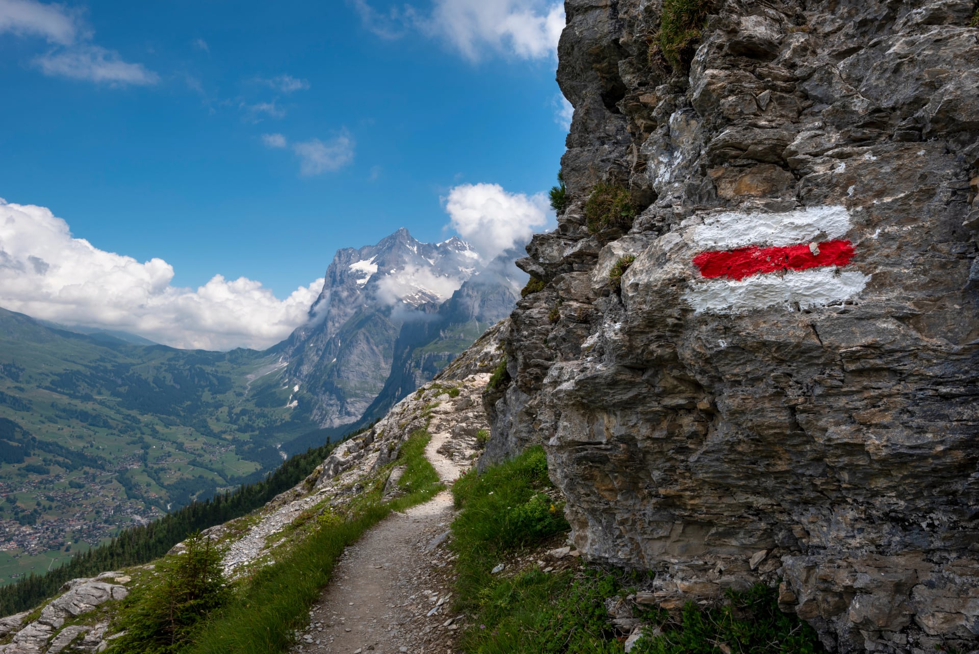 Segni dipinti su un sentiero dell'Eiger con la valle di Grindelwald sottostante e il picco del Wetterhorn dietro, Grindelwald, cantone di Berna, Svizzera