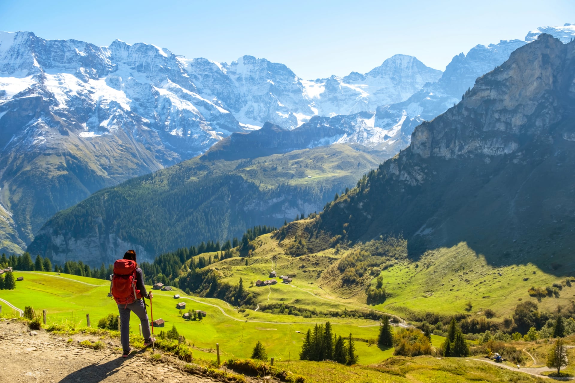Femme sportive se tenant devant des montagnes enneigées et appréciant la vue de la nature suisse. Passion du voyage, sport, beauté dans la nature.