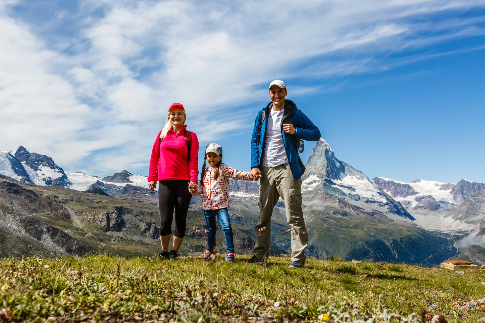 Famille heureuse avec un petit enfant faisant de la randonnée en montagne en Suisse en été. Jeunes gens s'amusant dans la nature. Concept de voyage, famille amicale