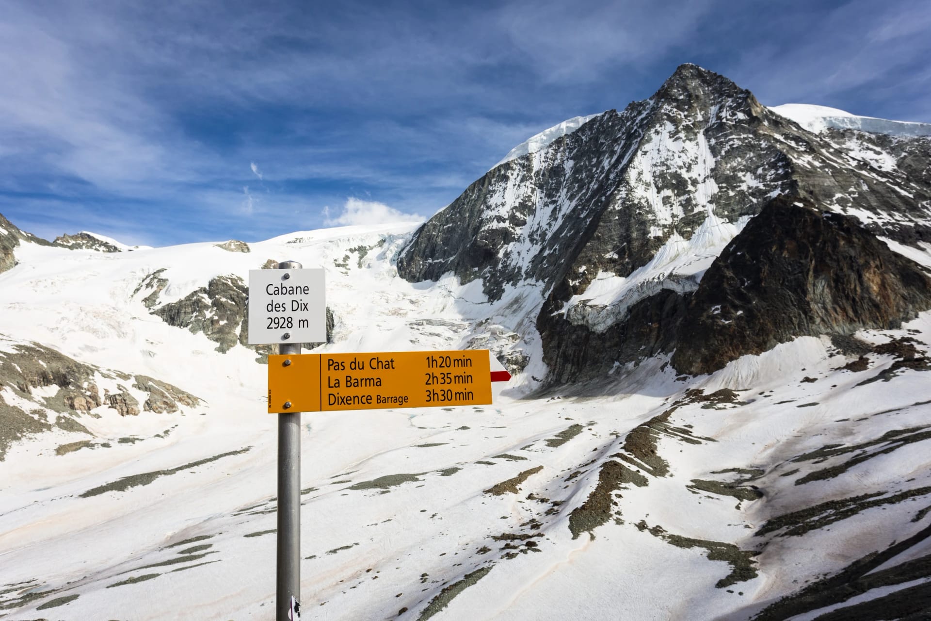Hiking trail distance sign with the Mont Blanc de Cheilon peak, at 3870m, in Canton Valais in the Swiss alps in Switzerland on a sunny summer day