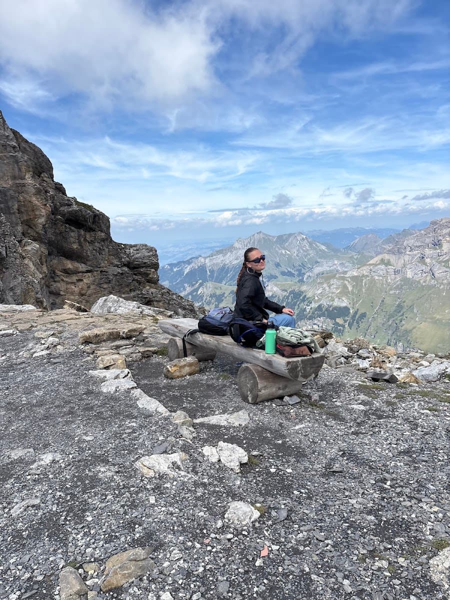 Hiker sitting on a wooden bench overlooking mountain peaks