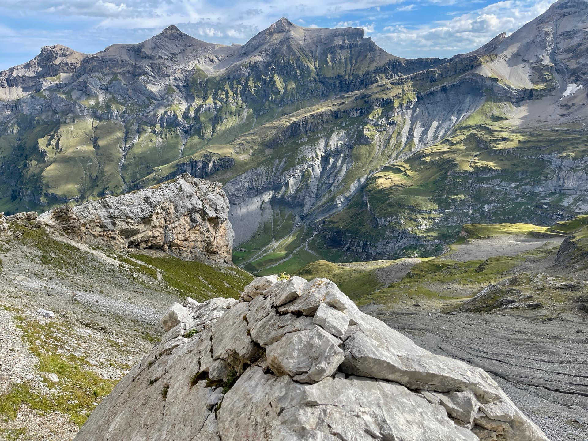 Limestone outcrop above deep alpine valley with rugged mountain peaks